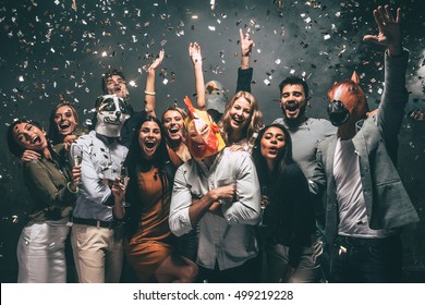 This Is My Year! Group Of Young People In Animal Masks Throwing Confetti And Looking Happy 