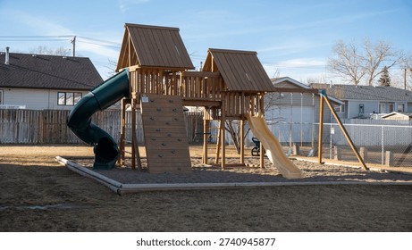 This outdoor swing set is the Backyard Discovery Skyfort II, made from cedar wood. It includes a treehouse, a green spiral slide, swings, and a flat slide.