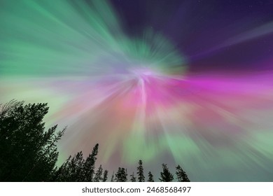 This photo captures the breathtaking northern lights (Aurora Borealis) illuminating the night sky above a mountain village with vibrant colors over snow-capped peaks and wooden cabins. - Powered by Shutterstock