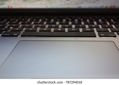 This is a photo of computer or notebook. It has a silver colour.  This photo is a focus on the a keyboard and touchpad.