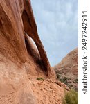 This photo features the impressive Longbow Arch in Moab, Utah, highlighting its graceful curve against a storm sky. The striking rock formation exemplifies the area