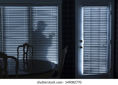 This Photo Illustrates A Silhouette Of A Burglar Or Thief Sneaking Up To Back Door At Night. View From Inside The Residence.