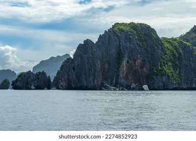 This photo showcases the stunningly rugged coastline of the Philippines. A series of rocky outcroppings, worn smooth by the lapping waves, stretch out to the horizon, while the turquoise sea swirls. - Shutterstock ID 2274852923