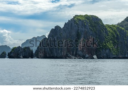 This photo showcases the stunningly rugged coastline of the Philippines. A series of rocky outcroppings, worn smooth by the lapping waves, stretch out to the horizon, while the turquoise sea swirls.