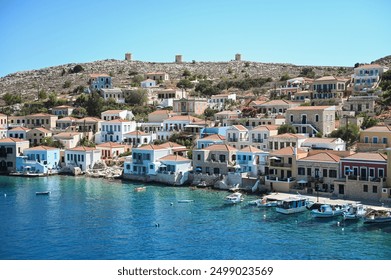 This photo shows the picturesque coastal village of Chalki, Greece. Traditional colorful houses with charming balconies line the waterfront, creating a vibrant contrast with the Aegean Sea! - Powered by Shutterstock