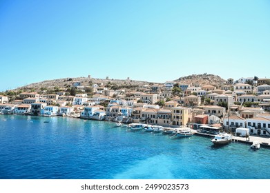 This photo shows the picturesque coastal village of Chalki, Greece. Traditional colorful houses with charming balconies line the waterfront, creating a vibrant contrast with the Aegean Sea! - Powered by Shutterstock