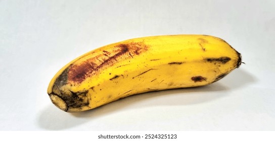 This photo shows a ripe banana. The banana is yellow in color and has some brown spots on its skin. Isolated on a white background. - Powered by Shutterstock