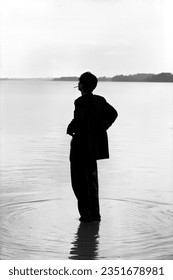 This photograph captures the image of a man smoking on the water's surface under the rain-soaked sky. With its black and white tones, it draws attention to the solitary figure amidst the surrounding s
