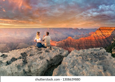 This is a photograph of a man and  a woman sitting on the edge of the rim, having great conversation during the Grand Canyon sunset