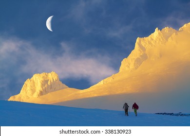 This Is A Photograph Of A Nature Scene In Mt. Hood With Two Persons Snowshoeing/hiking Toward The Peak. Photo Was Taken Around Sunset Hour With Moon And Clouds.