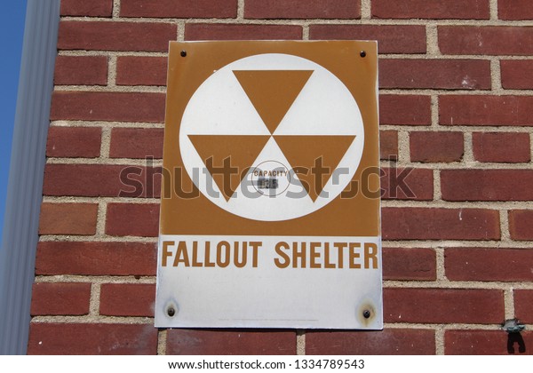 This a picture of a old vintage fallout shelter\
sign taken on an old\
building.