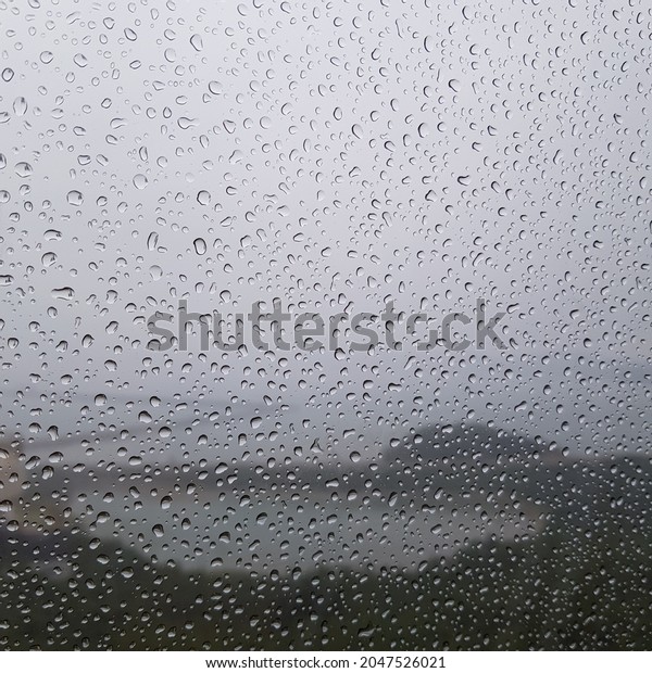 This is a picture of a window surrounded by
raindrops in a cable car on a rainy
day.