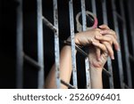 This powerful image captures hands grasping prison bars, symbolizing captivity and despair. The dim light adds an atmosphere of isolation and vulnerability.