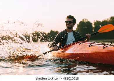 This Is The Real Life! Handsome Young Smiling Man Splashing Water While Kayaking On River