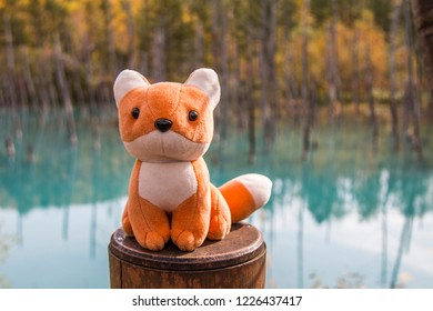 This red fox stuffed toy is sitting on the fence with background of Blue Pond that located at Biei Town, Hokkaido- Japan. This photo was taken during autumn season on the middle of October 2018. - Powered by Shutterstock