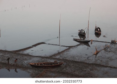 This is a river side where two fishermen boat is waiting and a trying to catch crabs.