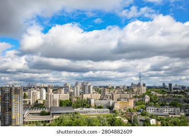 This scene features a wide view of a city skyline filled with tall buildings and greenery. The sky is partly cloudy and the sun is shining in the middle of the day.