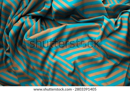 This scene showcases a textured background featuring lines in contrasting colors. The setting appears to be a studio dedicated to fabric design. The visual captures the flow and drape of the material.