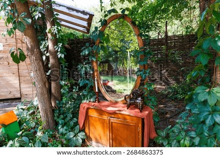 This serene image captures a rustic mirror nestled among trees and greenery, accompanied by a small table and decorative elements, creating a peaceful outdoor setting.