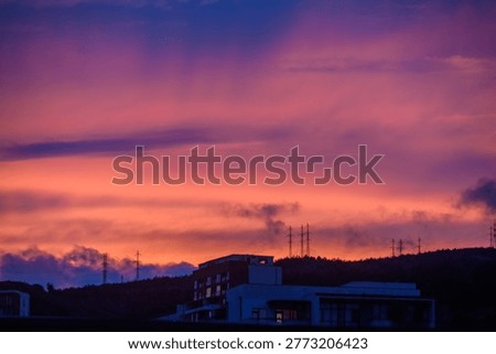 This shot captures a dramatic sunset over the hills of Tbilisi, where the sky literally burns with rich purple, crimson, and orange tones. Dense cumulus clouds are torn by the setting sun's flames, illuminating them from below, creating the illusion