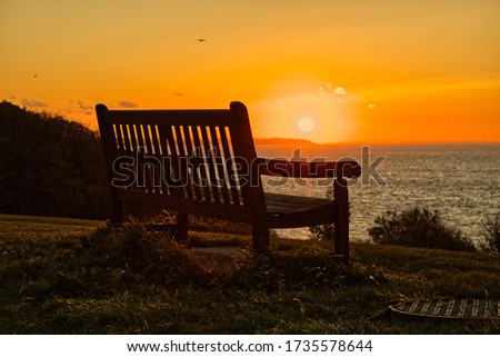 this is a shot of the sun setting behing a bench 