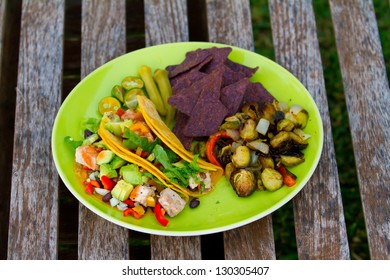 This Simple Meal Of Fish Tacos Is Served With Some Roasted Veggies And Chips On A Green Plate In Hawaii.