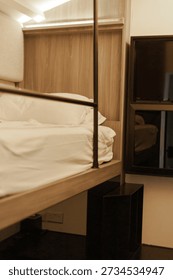 This small hostel room features a bunk bed, a television, and limited storage. It offers a simple lodging option for budget travelers in the city center during their visit.