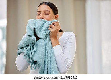 This smell should be bottled. Shot of a young woman smelling freshly cleaned laundry. - Shutterstock ID 2167990515