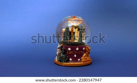 This snow globe featuring the city of Las Vegas has a deep blue background that creates a beautiful contrast with the white snowflakes and the iconic landmarks inside. It's a perfect way to display yo