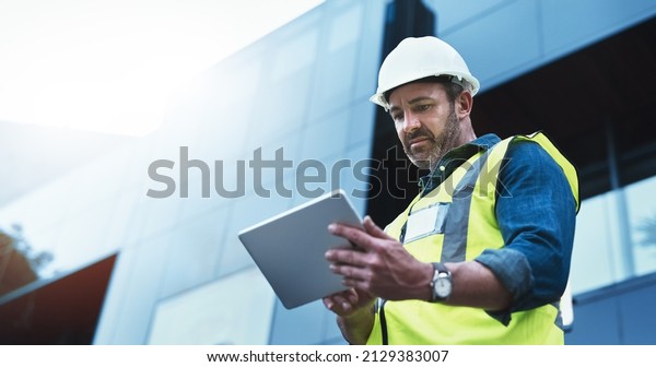 This\
software help me to keep track of everything. Shot of a engineer\
using a digital tablet on a construction\
site.