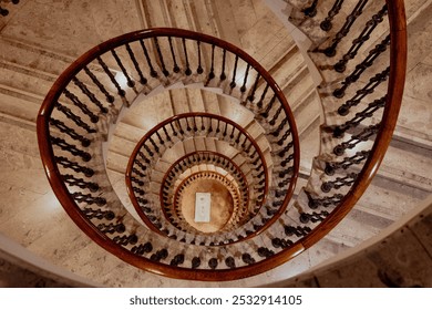 This spiral staircase showcases elegant architectural design with intricate wooden railings and a marble base. Captured from above, it creates a mesmerizing sense of depth, symmetry, and timeless beau - Powered by Shutterstock