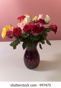 This Is A Still Life Photograph Of Two Dozen Roses In A Ruby Colored Vase.