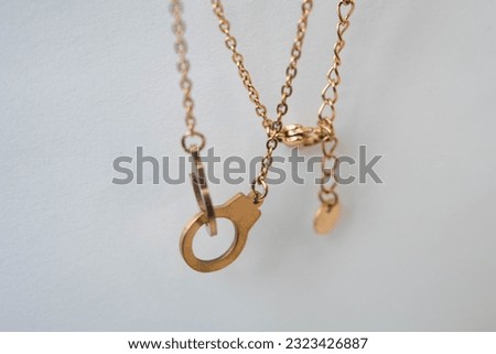 This stock photo features two gold chains connected together with two smaller gold chains attached
