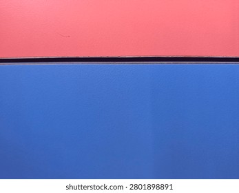 This striking and modern abstract composition features a bold horizontal split between two vibrant and contrasting color blocks. The top section is a warm coral-red or salmon-pink hue, while the bottom section consists of a deep, saturated blue. The two color fields are separated by a distinct, thin black horizontal line, which adds a sharp graphic element and a sense of structural balance to the image. This minimalist design is perfect for contemporary projects that require a clean and impactful visual statement. The clean lines and bold color choices make it highly effective for use in graphic design, website headers, magazine layouts, or as a dynamic background for social media advertising and posters. The high contrast between the warm and cool tones creates a visually stimulating effect that captures the viewer's attention immediately. This versatile image can represent themes of duality, balance, and modern art, making it a valuable asset for designers looking to incorporate a touch of minimalist sophistication into their work. The flat color application gives it a clean, professional look suitable for tech-oriented or design-forward brands that value bold aesthetics and geometric simplicity. It offers a perfect space for text overlay in various layout configurations.