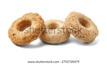 This studio photograph features three golden-brown breakfast cereal loops lined up against a deep white backdrop. The sharp focus and lighting accentuate the distinct, porous texture and circular structure of each oat-based ring. This image is well-suited for advertisements, health and nutrition articles, food blogs, or any visual content emphasizing healthy breakfast choices and natural ingredients.
