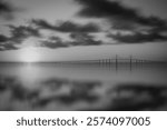 This stunning photo captures the iconic Sunshine Skyway Bridge from Fort DeSoto Park at sunrise. The soft golden light of the morning gently illuminates the scene, casting warm tones across the tranqu