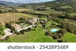 This stunning photo captures the picture-perfect landscapes of Tuscany, where beautiful nature meets charming architecture. In the foreground is a cozy villa with a traditional terracotta roof, surrou