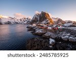 This stunning photo captures the picturesque Lofoten Islands in Norway, with charming red cabins set against dramatic, snow-covered mountains at sunset. Perfect for any travel or nature enthusiast