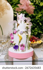 This stunning threetier cake features vibrant flowers, elegant gold accents, and a lively 1 on top, making it a perfect centerpiece for any joyful celebration