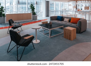 This stylish office lounge area features a blend of modern and comfortable seating options, including plush armchairs and contemporary swivel chairs, set a sleek glass coffee table. - Powered by Shutterstock