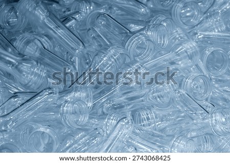 This technical visual features a collection of PET preforms, the essential semi-finished intermediate in bottle manufacturing. Each preform is produced via high-pressure injection molding, featuring a precisely threaded neck finish that remains constant while the body is later reheated and expanded.