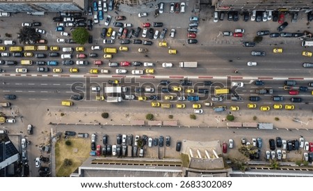 This top-down shot captures heavy traffic on a road in Douala, Cameroon, showcasing numerous cars and taxis. It illustrates the city's bustling transportation.