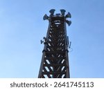 This tower is visible several parabolic antennas and sector antennas installed, which function to receive and transmit telecommunication signals such as cellular signals (2G, 3G, 4G, 5G).