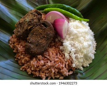 This Is A Traditional Meal Typical Of The Southern Province  Of Sri Lanka . Cooked Raw Red Rice , Sri Lankan Sour Fish Curry ( Malu Abul Thiyal) , Grated Coconut  And A Few Raw Chilli Pods .