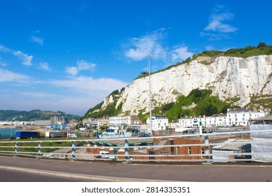 This is a view of the famous White Cliffs of Dover in Kent, England.The cliffs are primarily composed of chalk.The area is a major coastal landmark facing the Strait of Dover and France.The image also shows parts of the Port of Dover, a significant commercial harbor and ferry terminal.Seen while traveling on Jubilee Way A2  Highway