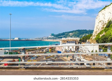 This is a view of the famous White Cliffs of Dover in Kent, England.The cliffs are primarily composed of chalk.The area is a major coastal landmark facing the Strait of Dover and France.The image also shows parts of the Port of Dover, a significant commercial harbor and ferry terminal.Seen while traveling on Jubilee Way A2  Highway