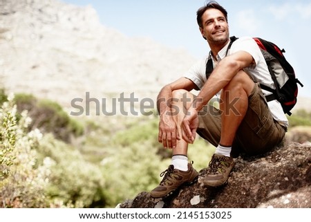 This view stretches for miles..... Handsome male hiker smiling while seated on a mountain top.
