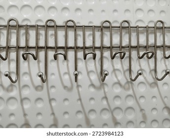 This is a wall-mounted multi-hook rack, typically made of stainless steel or chrome-plated metal. It features a row of hooks often used for coats, keys, or kitchen utensils attached to a decorative 