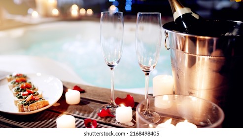 This is where you want to come celebrate your love. Shot of a beautiful setting of champagne and treats near a hot tub at night. - Shutterstock ID 2168498405