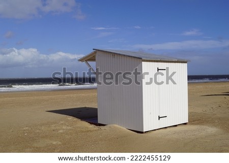 This is a white beach cabin where people store their beach gear in summer. The cabin stands on the sand of the Belgian beach.